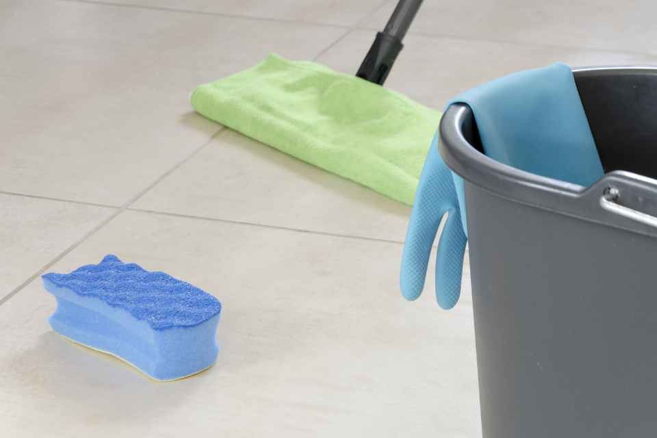 dry mop, sponge, and bucket cleaning supplies on tile floor